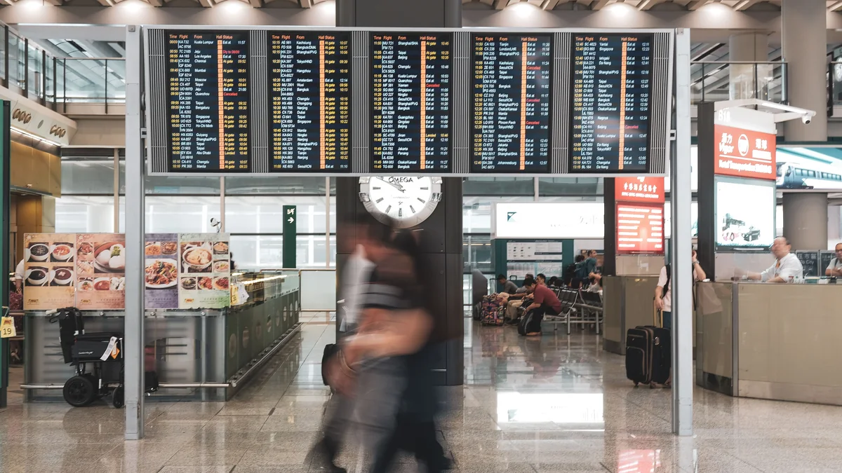 Resenärer passerar avgångstavlorna i en flygplatsterminal